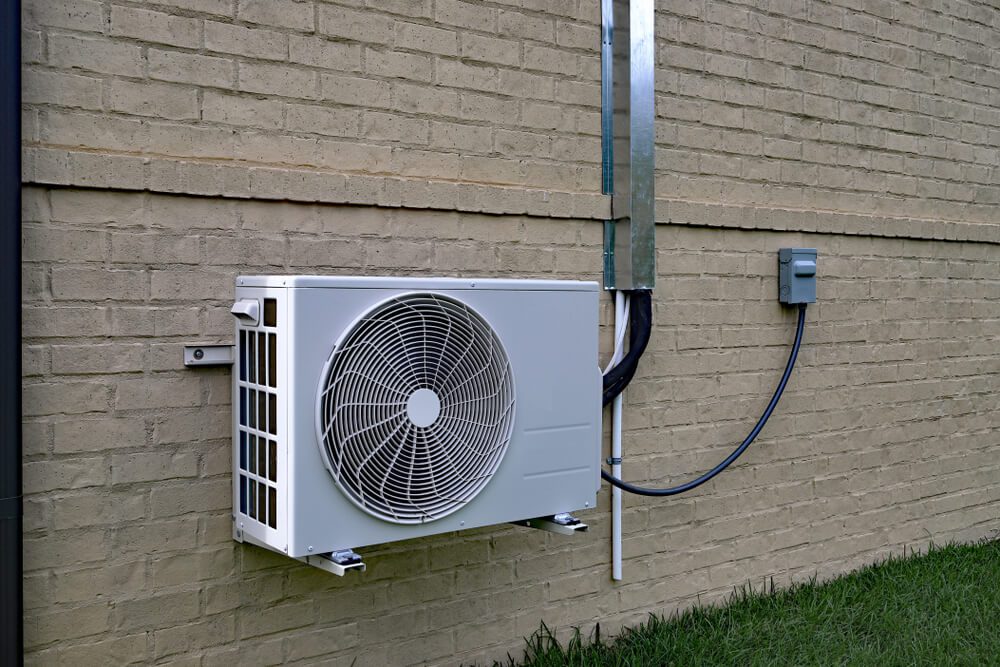 air conditioner mini split compressor system mounted on brick outdoors